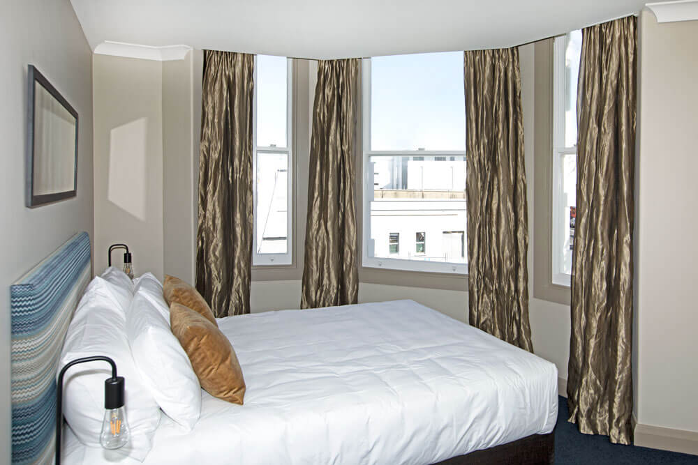 Photo of the Bryne Heritage Suite showing the Luxury Queen Bed, and Bay Window